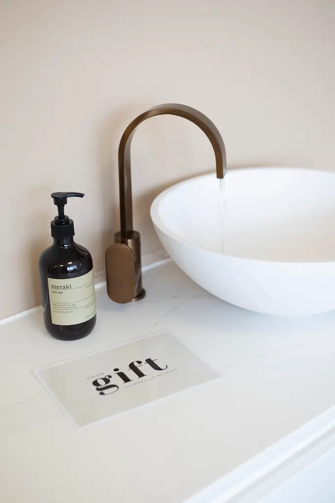 Minimalistische waskom met stromend water in een rustige behandelruimte van De Huidskillskliniek